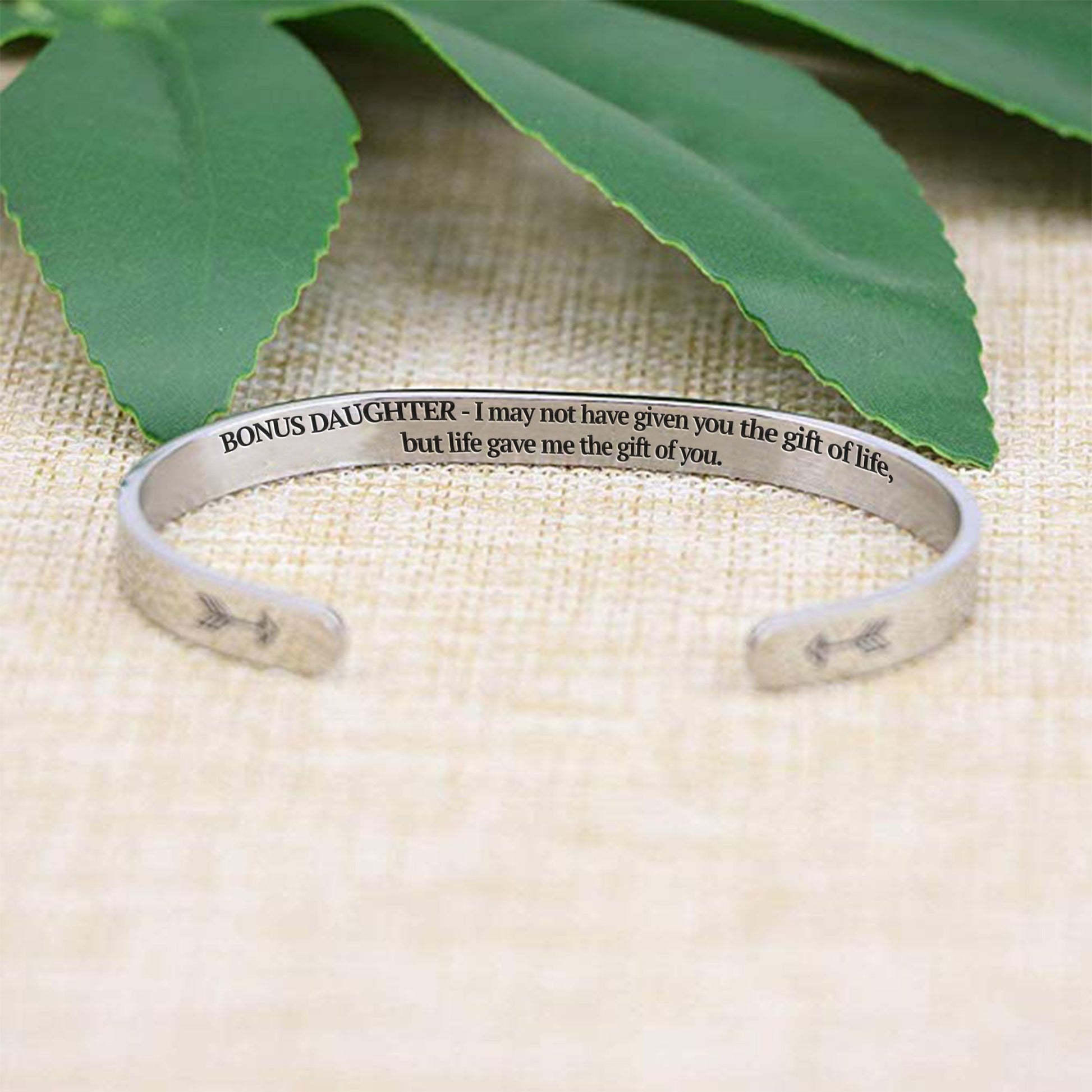 I may not have given you the gift of life but life gave me the gift of you bracelet with silver plating with message in focus on a burlap surface with a leafy background